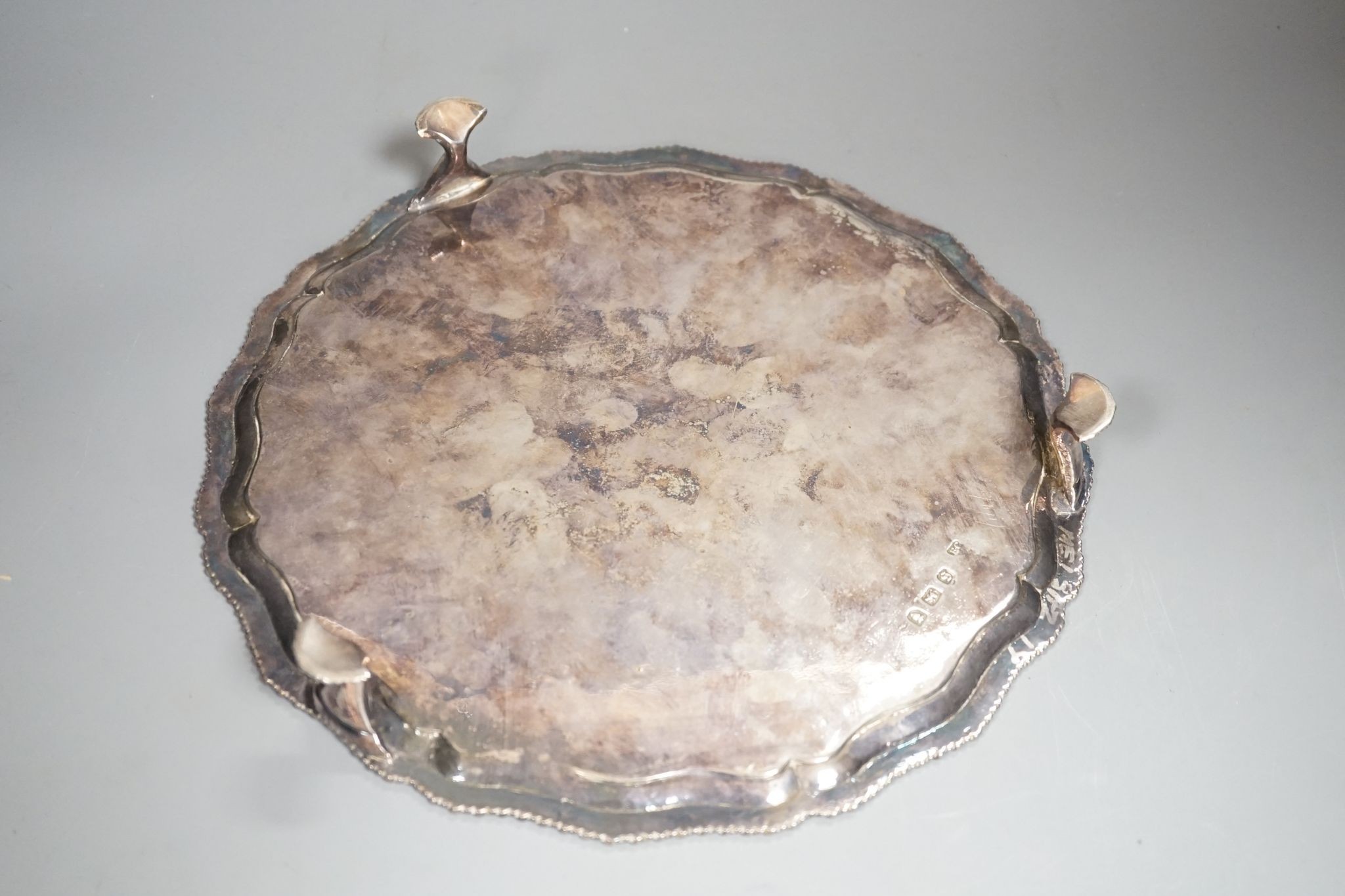 A George III silver salver, with gadrooned border, on three shell feet, Ebenezer Coker, London, 1773, 28.1cm, (repairs), 20.5oz.